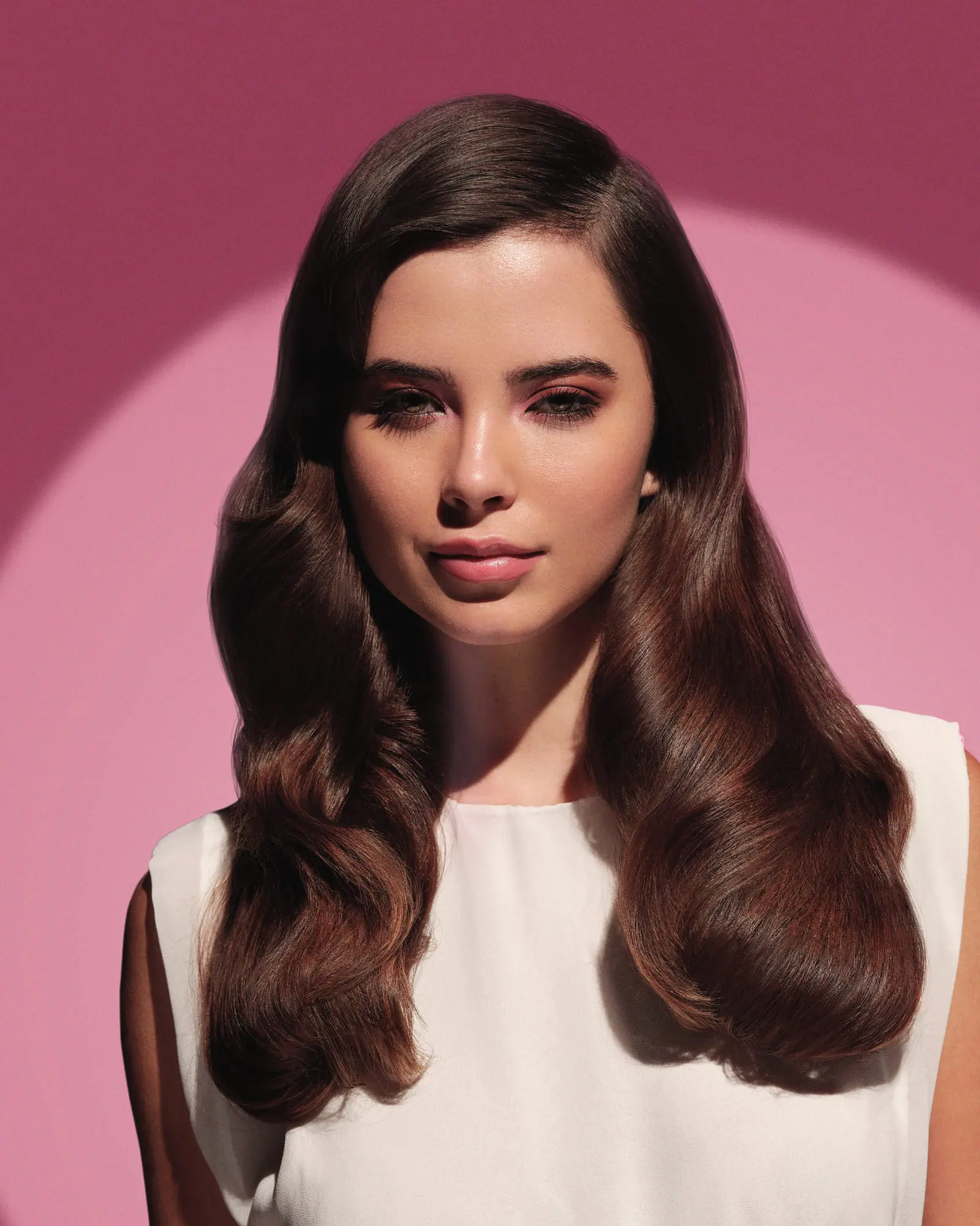 Modelo de ondas castanhas e vestido claro, fundo rosa
